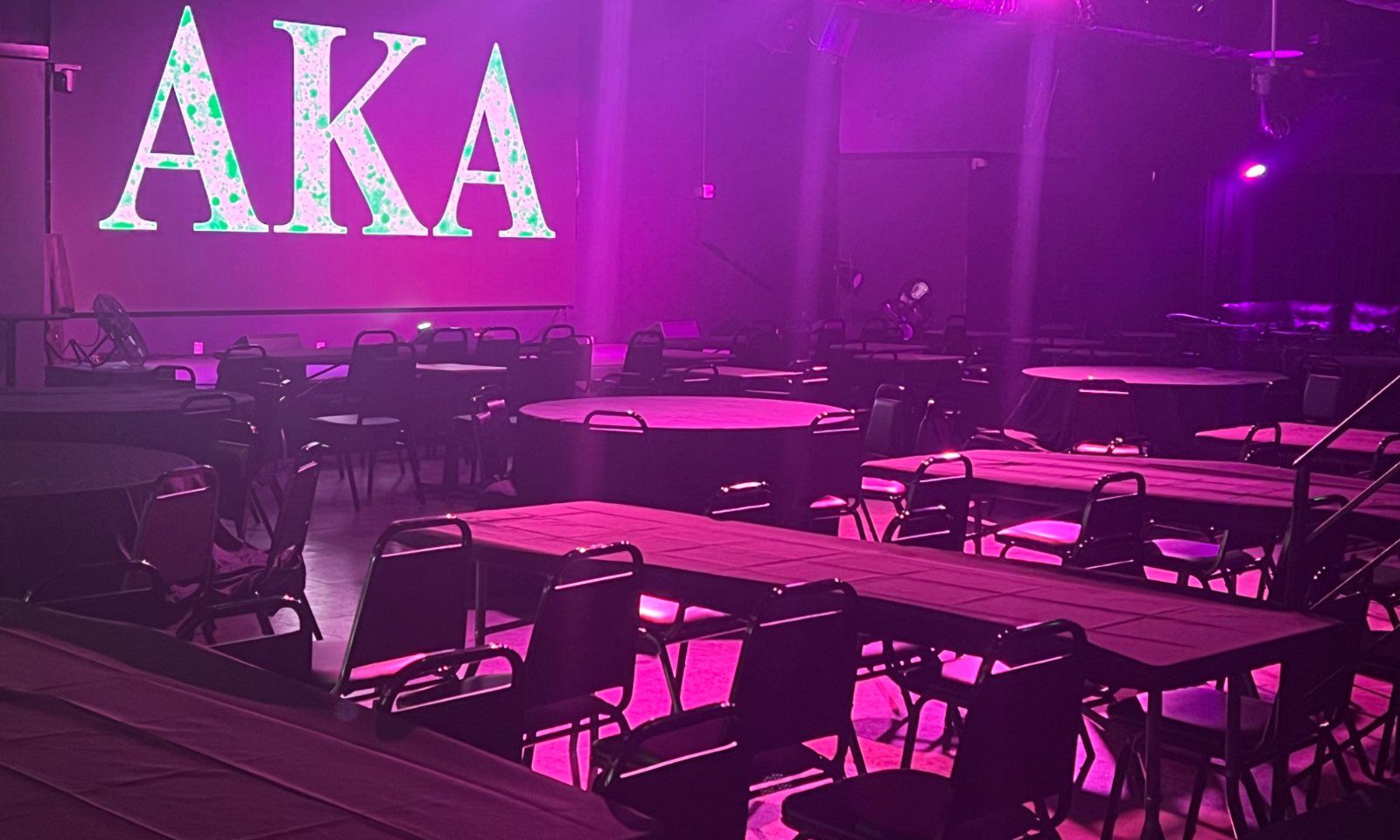The main room lit in pink and green for an AKA event at La Familia