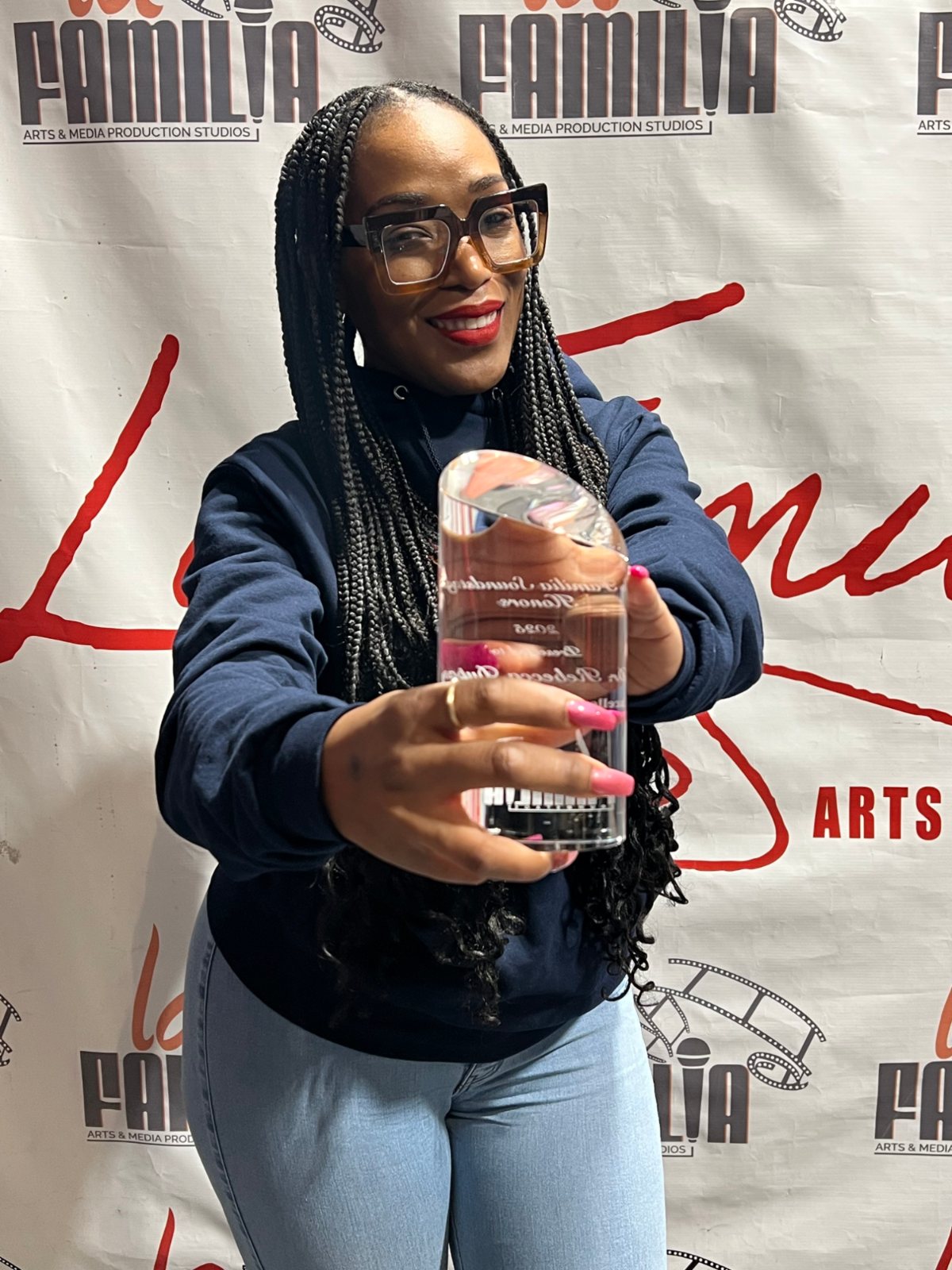 An honoree holding her award at the La Familia step and repeat