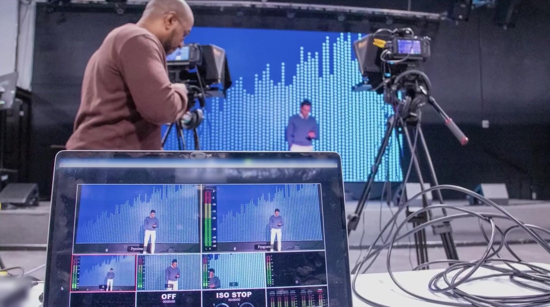 Camera operator filming a stage presentation at La Familia with a live multi-camera feed